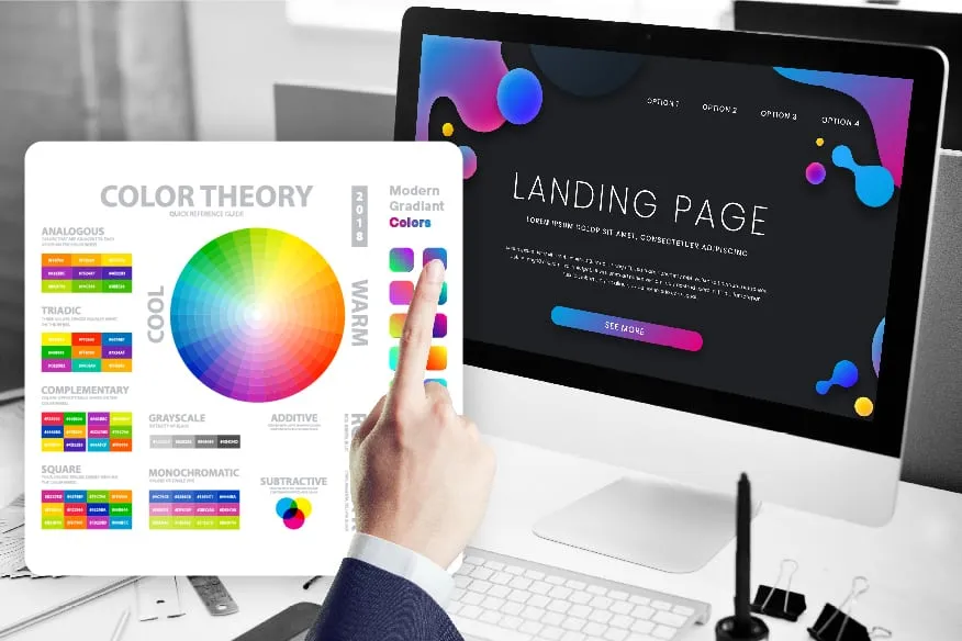 A man is pointing at a computer screen with a color wheel on it.